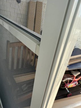 Yakından bakıldığında, yazın sivrisinekleri korumak için bir pencere ekranı ve ahşap mobilyalar görünür.