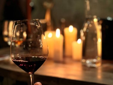 Tiflis, Gürcistan - 27 Nisan 2025: Misafirler mum ışığında Tiflis şarap müzesinin rahat atmosferinin tadını çıkarırken bir yandan da bir qvevri 'den doğal şarabın tadını çıkarıyorlar.