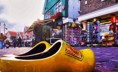 volendam, netherlands - 08 October 2022: giant wooden shoes on harbor front of dutch village with souvenir shops and terraces