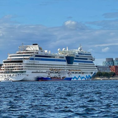 Kopenhag, Danimarka - 25 Temmuz 2023: Mavi gökyüzü gününde şehre giren bir yelkenli ve modern ve büyük bir yolcu gemisi