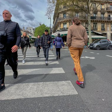 Paris, Fransa - 11 Nisan 2023: Tipik bir Paris caddesi veya bulvarının yaya geçidinde bir adam yürüyor.