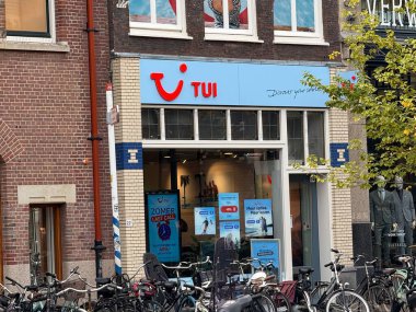 Den Haag, Hollanda - 22 Eylül 2025: Bir seyahat acentesi açık bir günde bisiklet ve dükkanlarla dolu canlı bir şehir caddesinde tabelalarını sergiliyor.