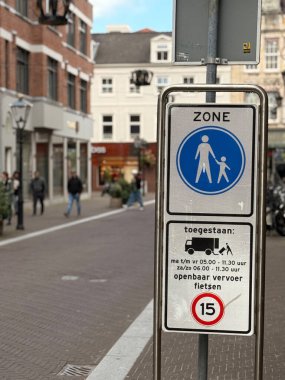 Den Haag, Hollanda - 22 Eylül 2025: Bir tabela, arka planda yürüyen ve alışveriş yapan insanların bulunduğu kentsel alanda yaya ve bisiklet bölgesini gösteriyor.