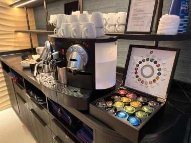 Lahey, Hollanda - 25 Eylül 2025: İyi organize edilmiş bir kahve istasyonunda bir nespresso makinesi fincanı ve renkli kahve kapsülleri yer alıyor