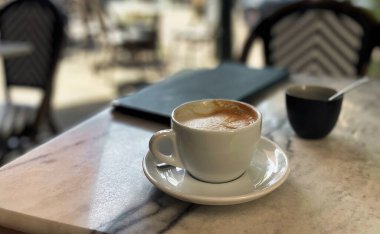 Senaar, Hollanda - Ağustos 06 2022: Avrupa 'daki mermer teras masasında kapuçinosu olan bir fincan tabağı