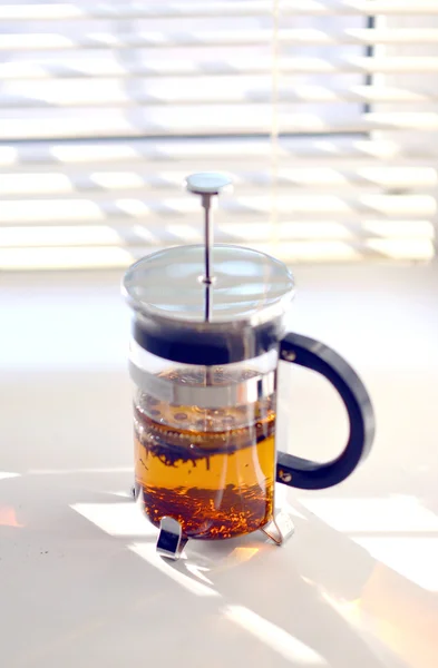 Стеклянный чайник, стоящий на стеклянном столе  . — стоковое фото