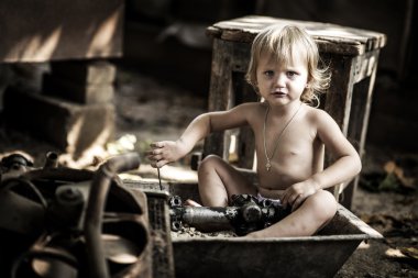 Küçük kız için araba yedek parça ortasında oturan.