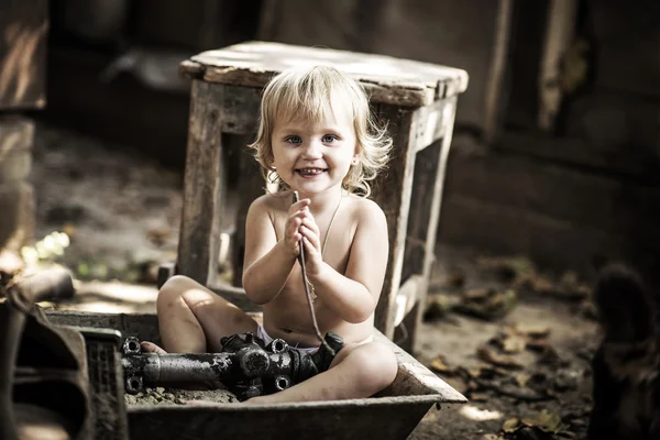 Little girl sitting in the middle of spare parts for cars. — Stock Photo, Image
