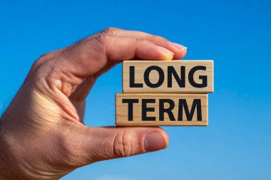 Mavi arka plandaki tahta bloklara yazılmış uzun vadeli bir mesaj. Kavramsal çağrı şimdi bir sembol. Boşluğu kopyala.