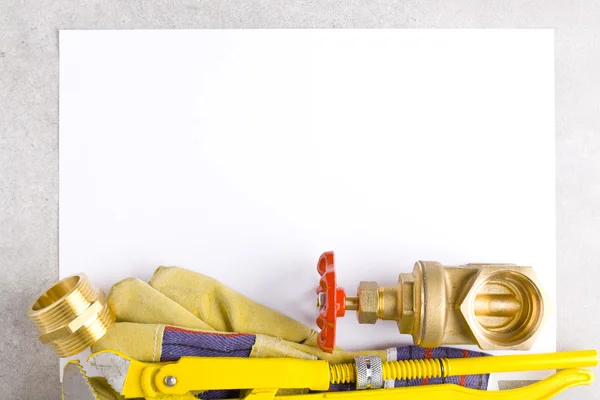 Moersleutel, werkhandschoenen en messing fittingen op vel papier. — Stockfoto