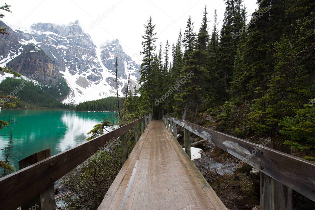 Wooden bridge at the Moraine lake by a rainy and misty day. Alberta, Canada