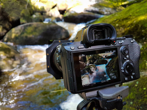 Camera on a tripid taking a long exposure shot of a river. Nobody