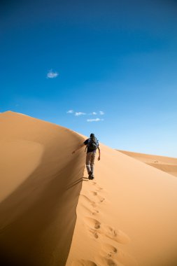 One person climbing big dune in the desert clipart