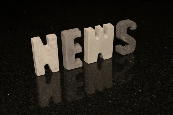 Word News as grey concrete letters on black tile — Stock Photo, Image