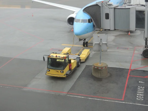 Самолет у ворот с желтым эвакуатором — стоковое фото