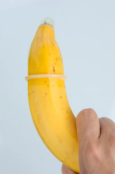 Condón sobre plátano en la mano sobre fondo blanco —  Fotos de Stock