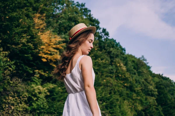 緑の夏の森を背景に藁帽子の若い女性 畑にドライフラワーの花束とドレスの美しい女の子 夏のドレスの女の子 — ストック写真