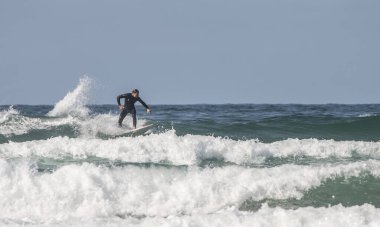 Fistral Sahili Newquay Cornwall 'da dalgaların tepesinde sörfçü.
