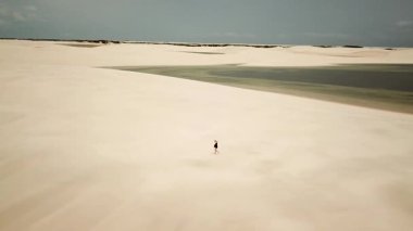 Lencois Maranhenses Ulusal Parkı kum tepeleri ve lagünlerle dolu. Rota Lagoa Azul, Maranhao, Brezilya 'ya koşan bir kız. Yüksek kalite 4k görüntü