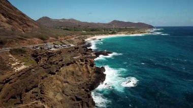 Honolulu 'nun doğu yakasındaki volkanik ve plajlı sahile yakın bir sahil yolu. Turkuaz kristal temiz okyanus ve güzel dağlar. İHA görüntüleri, Oahu Hawaii. Yüksek kalite 4k görüntü