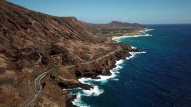 Honolulu 'nun doğu yakasındaki volkanik ve plajlı sahile yakın bir sahil yolu. Turkuaz kristal temiz okyanus ve güzel dağlar. İHA görüntüleri, Oahu Hawaii. Yüksek kalite 4k görüntü