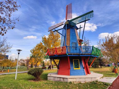 Sonbahar sezonu boyunca güneşli bir halk parkında canlı, renkli ahşap yel değirmeni minyatür yapısı
