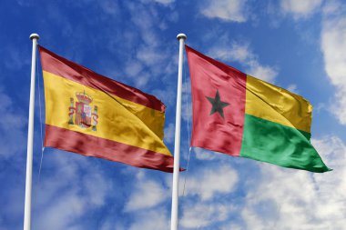 Mavi gökyüzünde dalgalanan İspanya ve Gine-Bissau bayrakları diplomasiyi, ticareti, stratejik ortaklığı ve birliği simgeliyor.