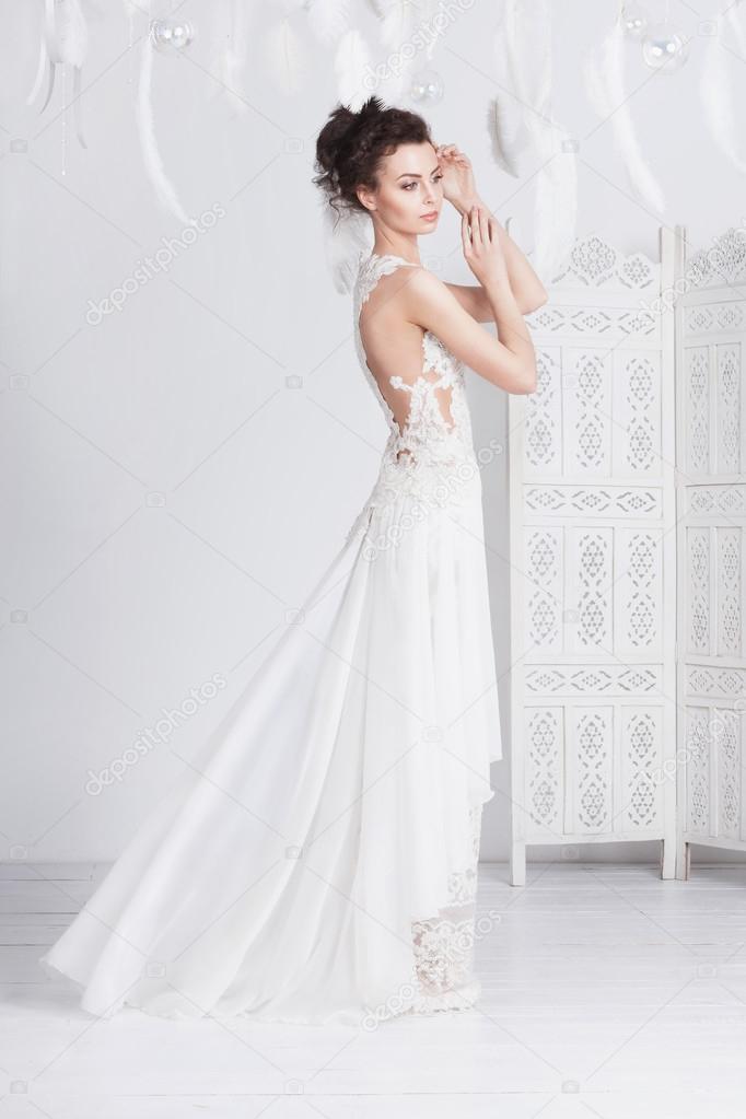 Tall and slim young bride in a luxurious lace wedding dress.