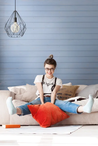 Young student sitting on a couch, her hands hanging down. She is tired, she is bored.