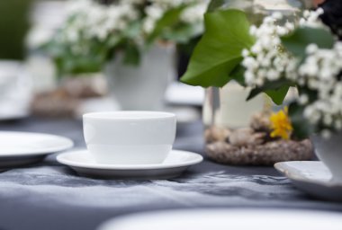 Alçakgönüllülükle düğün tablo dekore edilmiştir. Gotik romantizm, düğün Bahçe. El yapımı beyaz desenli siyah bir masa örtüsü üzerinde duran beyaz bardak