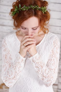 Young red-haired bride is praying for happyness clipart