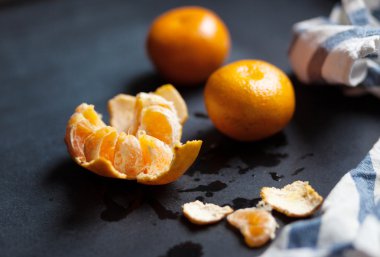 Üç mandalina çizgili bir keten havlu ile siyah masanın üzerinde yatan.