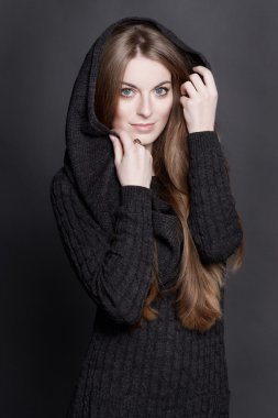 oung attractive woman with long, gorgeous dark blond hair and large blue eyes. She is dressed in warm gray knit dress with a hood