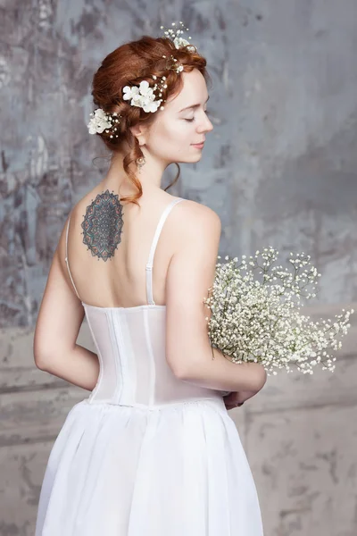 Giovane sposa dai capelli rossi in elegante abito da sposa. Lei è con lei di nuovo allo spettatore. I suoi occhi sono chiusi da sogno . — Foto Stock