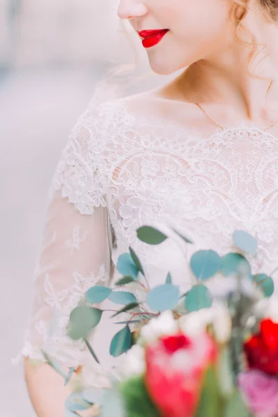 Bella sposa con labbra rosso brillante tiene bouquet da sposa da vicino — Foto Stock
