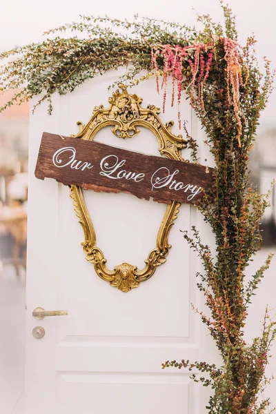 Porta branca decorada com flores e verde como símbolo de amor — Fotografia de Stock