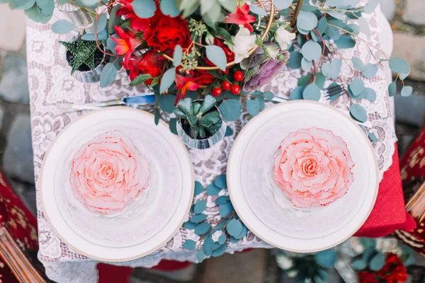 Witte bruidstaart gestileerd als bloem met rode boeket op houten achtergrond — Stockfoto
