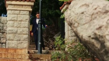 Mavi elbiseli şık damat Karadağ, Budva sevimli terrier ile merdivenlerden aşağı yürüyor