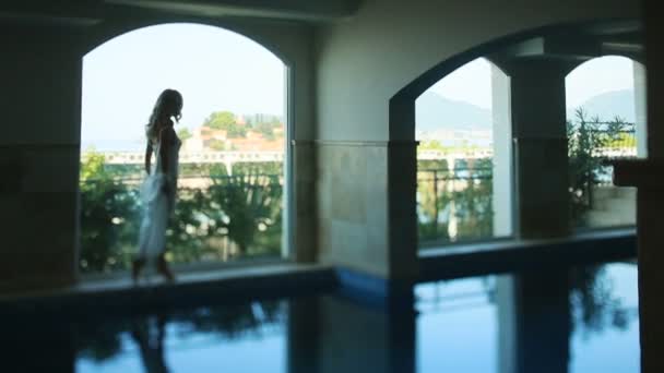 Silhouet van sexy bruid in witte doorschijnende robe lopen op terras in het hotel genieten van het uitzicht — Stockvideo