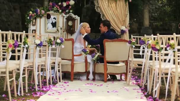 Glückliches Paar sitzt im Hochzeitszelt und küsst sich — Stockvideo