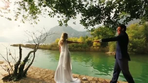 Fiatal esküvői pár csók a régi rakparton-Montenegro, Budva-a tenger és a hegyek a háttérben — Stock videók