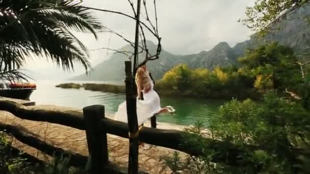 Bello sposo tiene e torce in aria la sua affascinante sposa sulla vecchia banchina — Video Stock