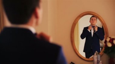 Yakışıklı damat aynada yansıması olarak görünüyor ve papyon düzeltir
