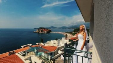 Sevimli sarışın gelin gelinlik ve arka plan üzerinde uzun peçe ile Budva, Karadağ'daki Sveti Stefan