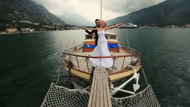 Pareja de boda cogida de la mano en la popa del barco que navega en el mar en Montenegro, Budva — Vídeo de stock