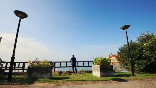 Noivo elegante desfrutando de bela paisagem marinha e céu azul claro em Montenegro, Budva — Vídeo de Stock