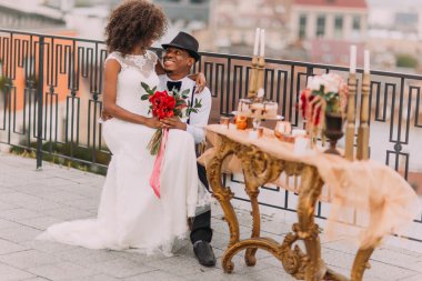 Mutlu Afrikalı gelin damadın dizlerinin üzerine oturarak gülümsüyor. Düğün günü