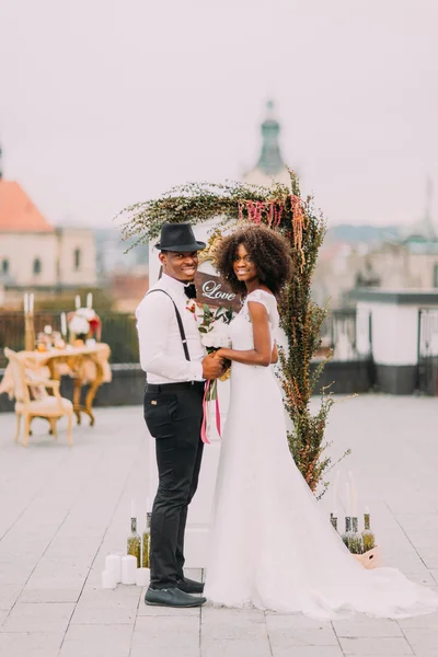 Casal de casamento alegre feliz sorrindo e de mãos dadas no telhado — Fotografia de Stock