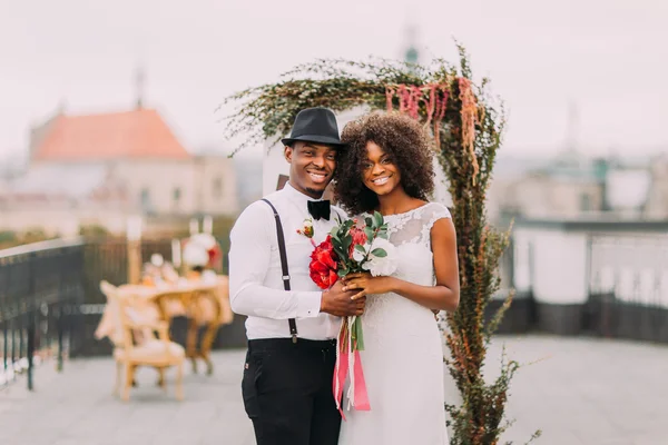 Довольно африканская свадебная пара весело улыбается и держится за руки — стоковое фото