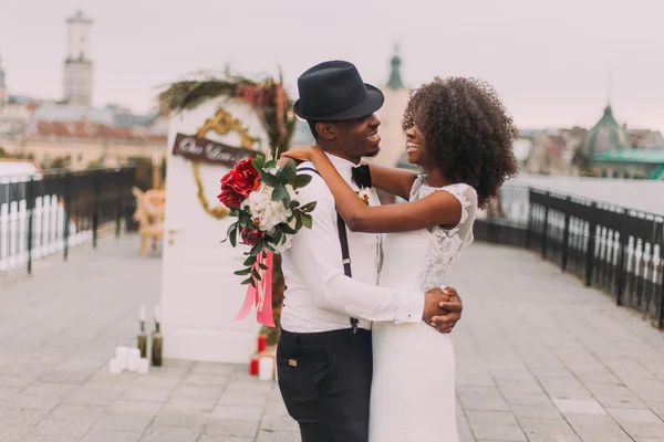 帽子と彼のかわいい花嫁のスタイリッシュなアフリカの新郎は幸せに笑います。結婚式の日 — ストック写真
